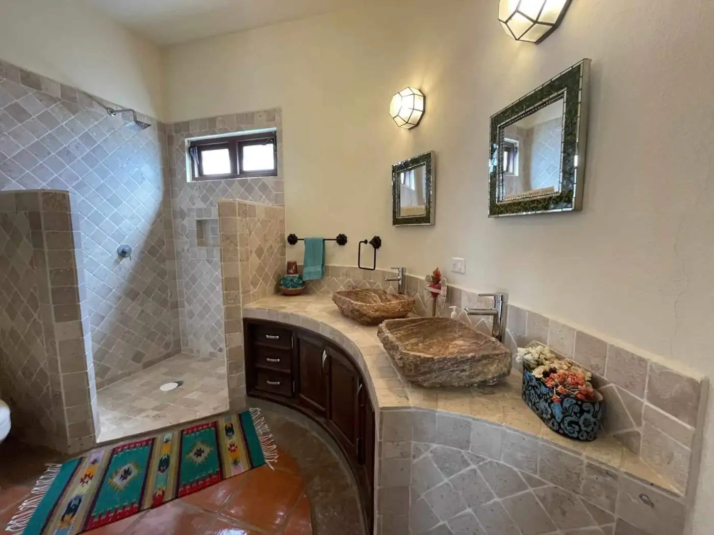 Luxury bathroom with stone sinks and walk-in shower, featuring modern fixtures and elegant decor.
