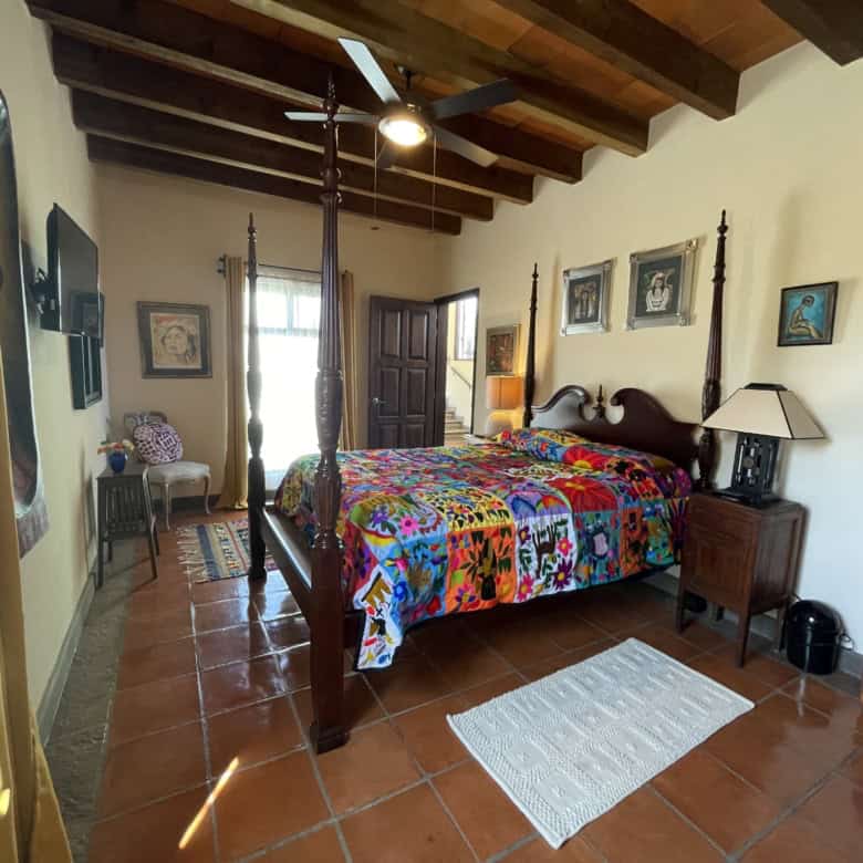 Cozy bedroom featuring wooden ceiling beams and colorful decor, perfect for a relaxing home environm.