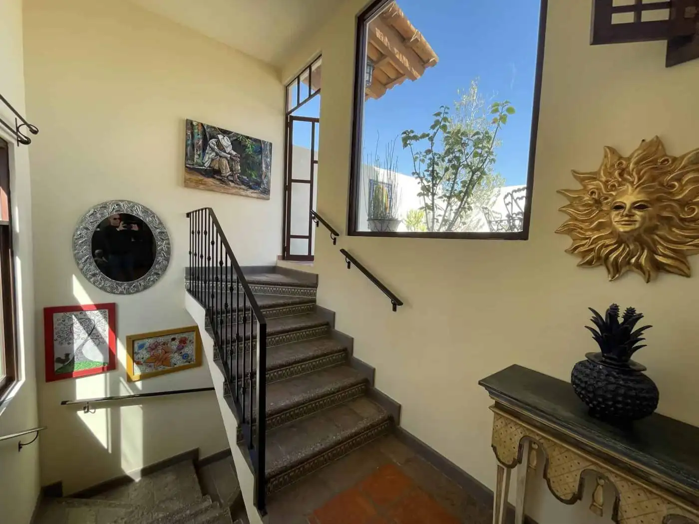 Bright interior staircase with artwork and decor, natural light, and plants.