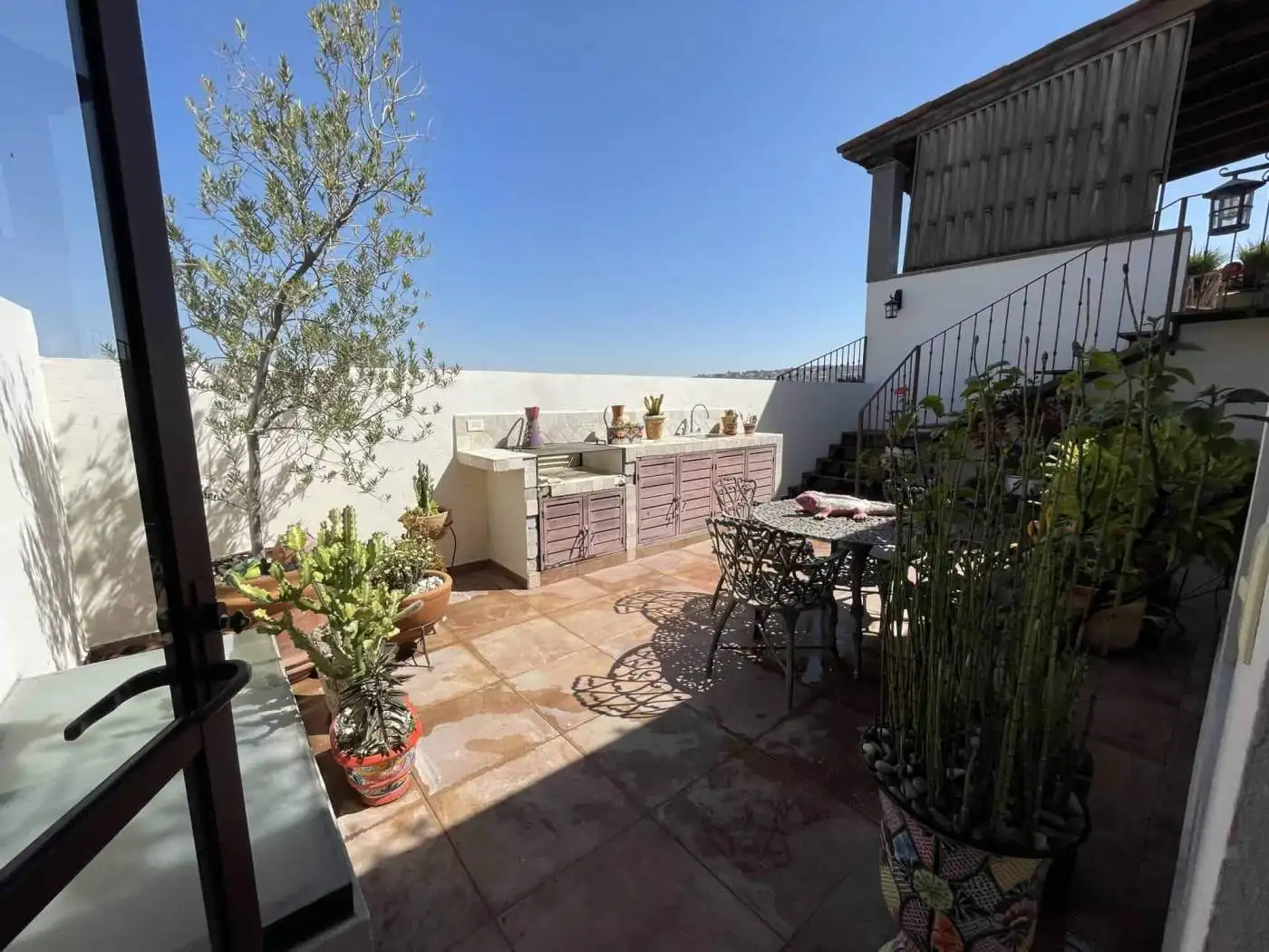 Rooftop terrace with outdoor furniture, potted plants, and scenic city views.