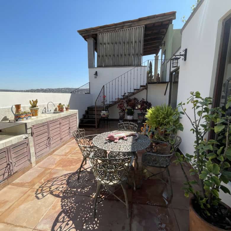 Rooftop terrace with outdoor dining set, potted plants, and sea view in a coastal property.