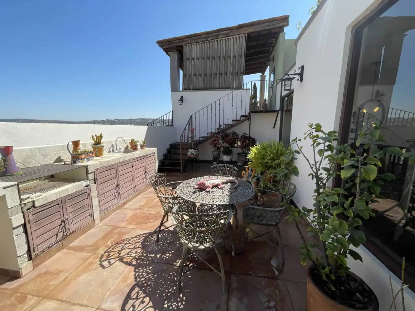 Rooftop terrace with outdoor dining set, potted plants, and sea view in a coastal property.
