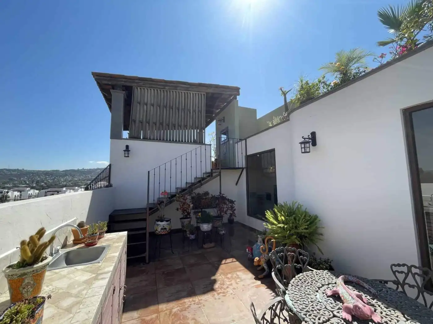 Rooftop terrace with outdoor furniture, potted plants, and city views in a contemporary property.