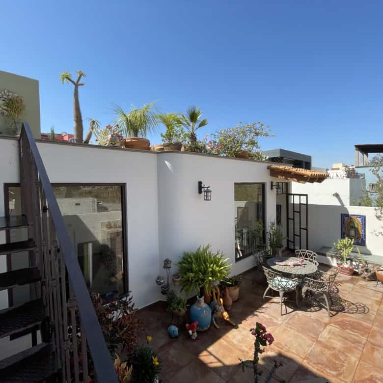 Rooftop terrace with outdoor seating, potted plants, and city views.