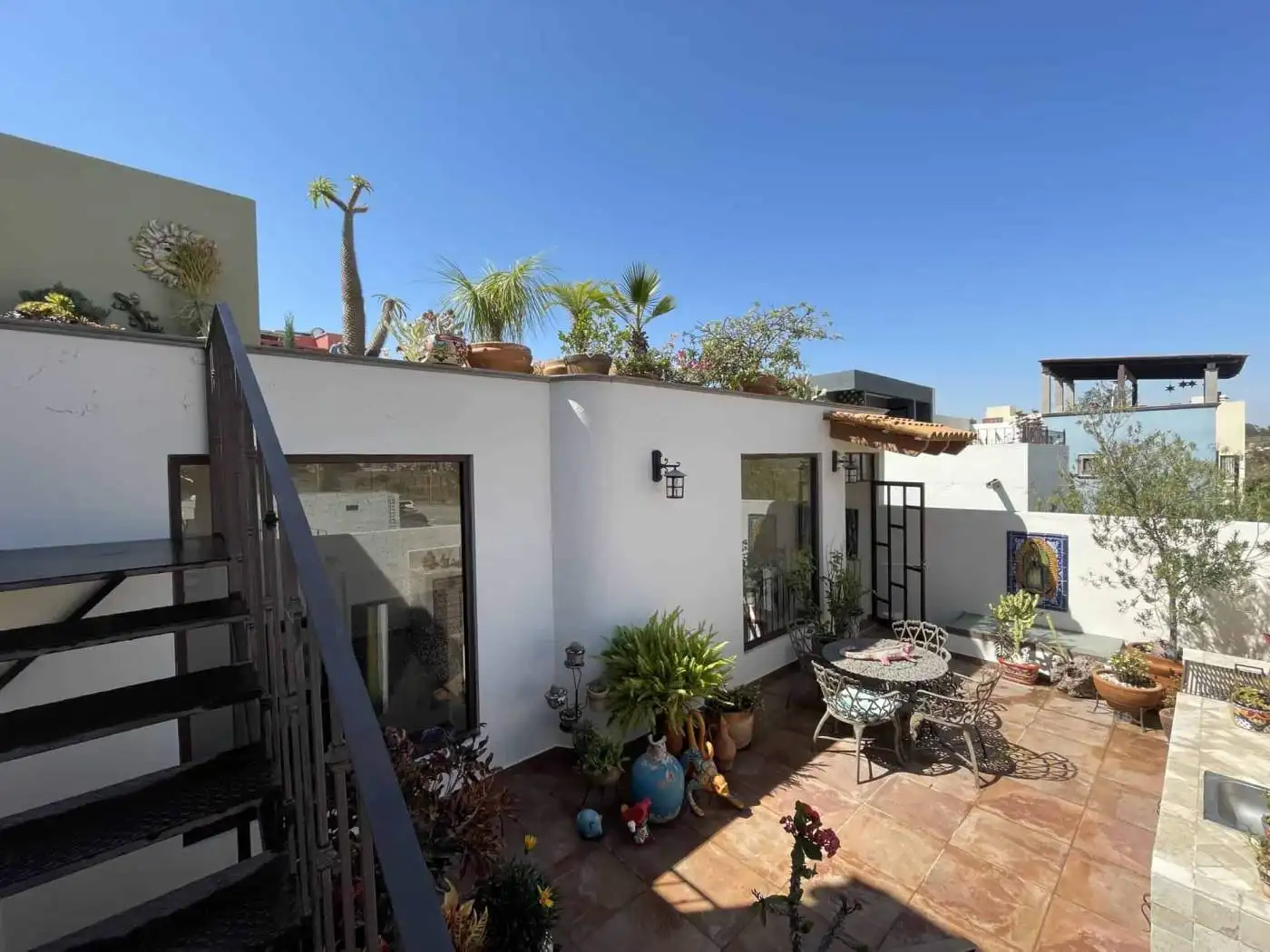 Rooftop terrace with outdoor seating, potted plants, and city views.