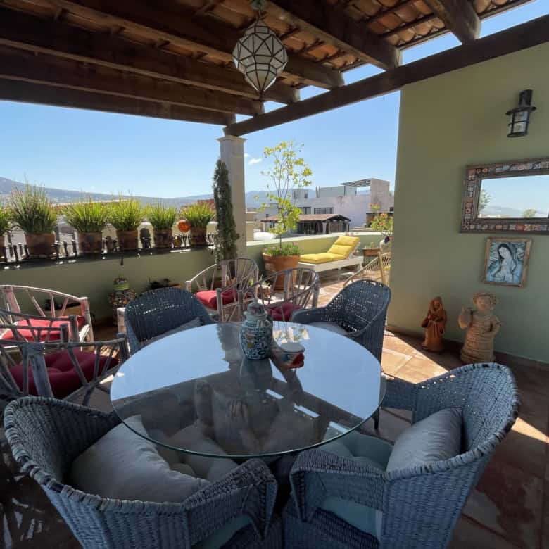 Rooftop terrace with outdoor seating, potted plants, and scenic city views under a wooden pergola.