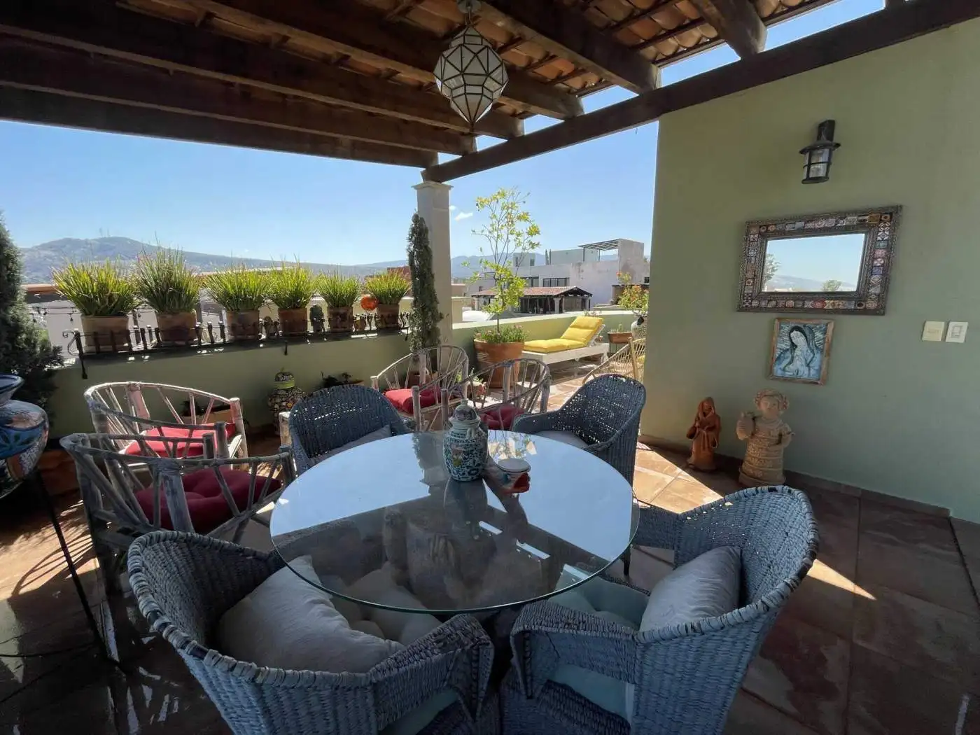 Rooftop terrace with outdoor seating, potted plants, and scenic city views under a wooden pergola.