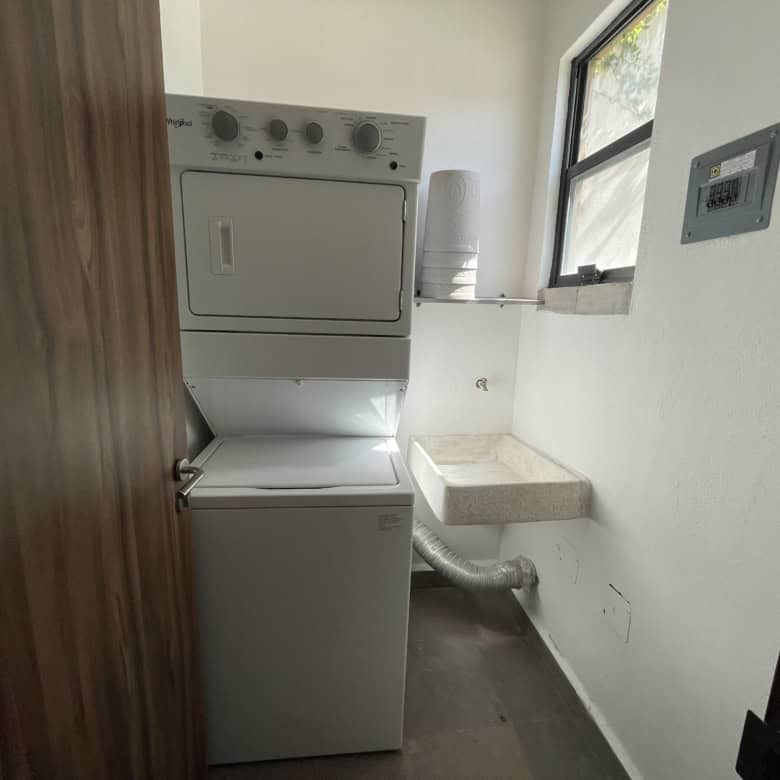Laundry room with stacked washer and dryer near window.