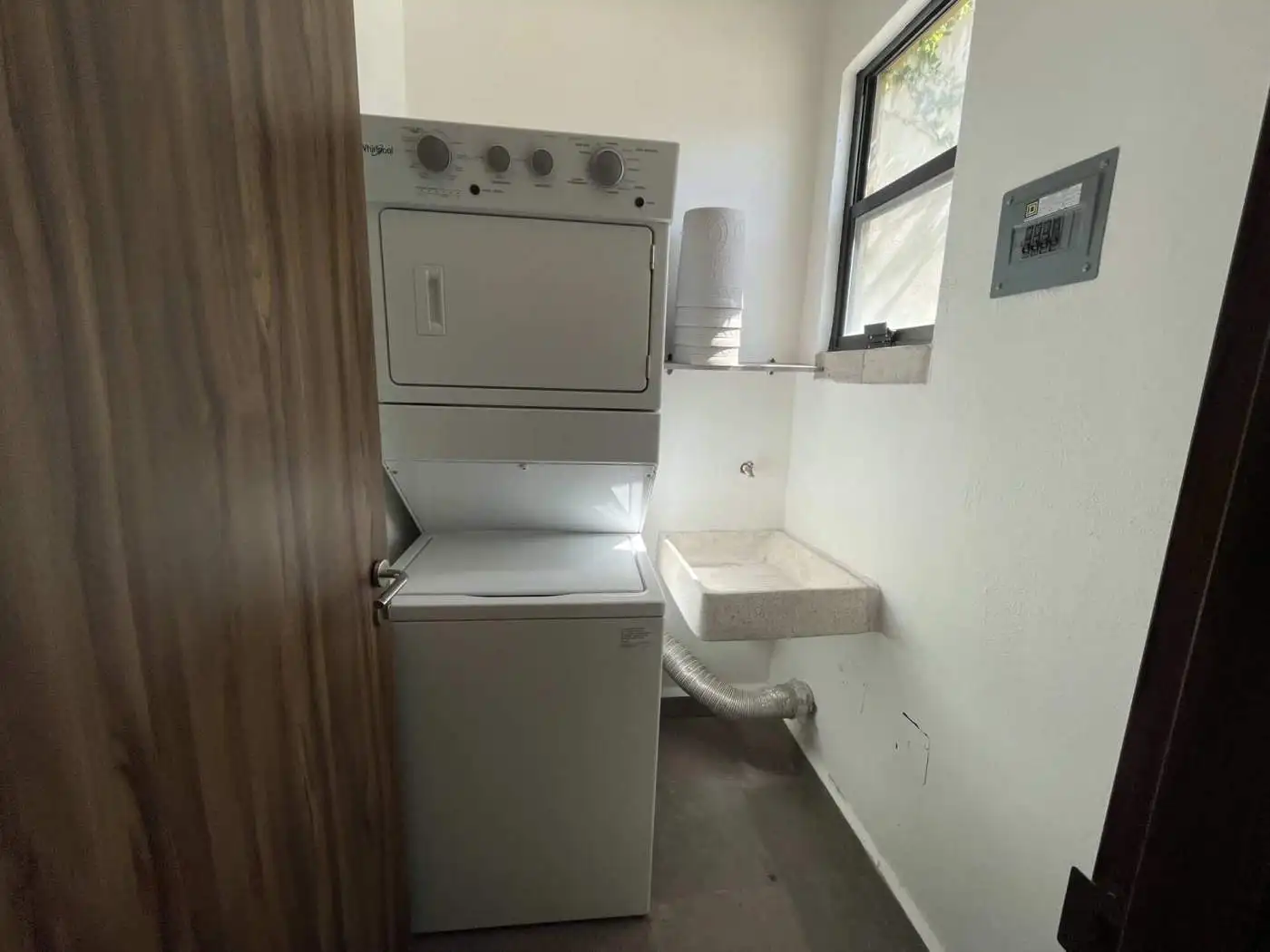 Laundry room with stacked washer and dryer near window.