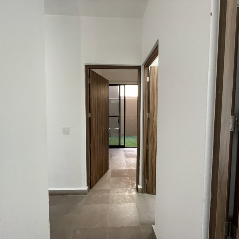 Bright hallway with wooden doors leading to outdoor space.