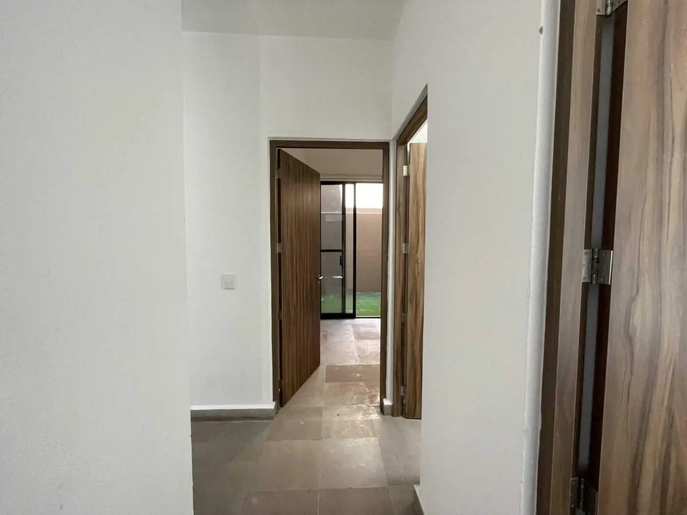 Bright hallway with wooden doors leading to outdoor space.
