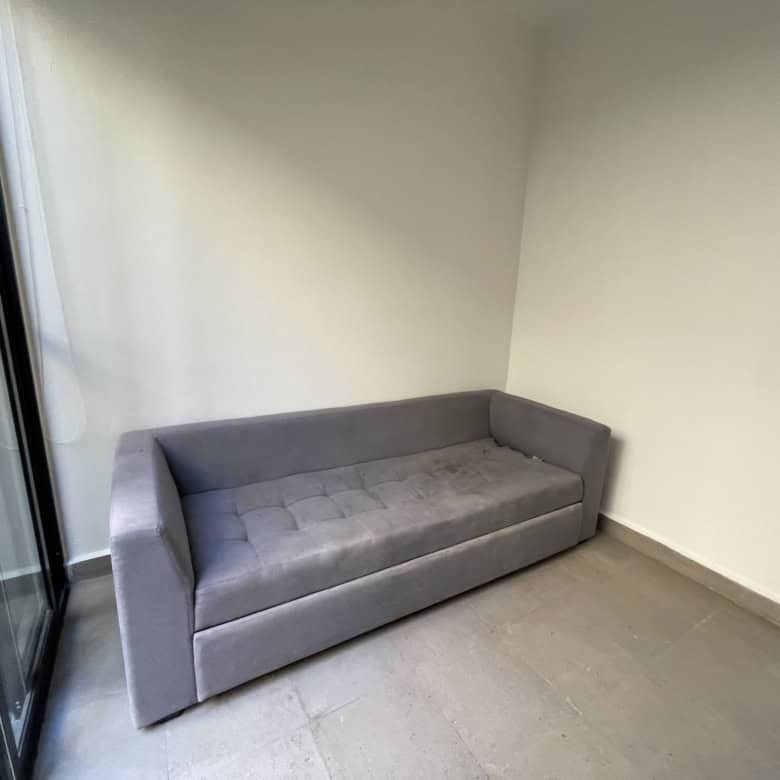 Modern gray sofa in a bright living room with large glass door.