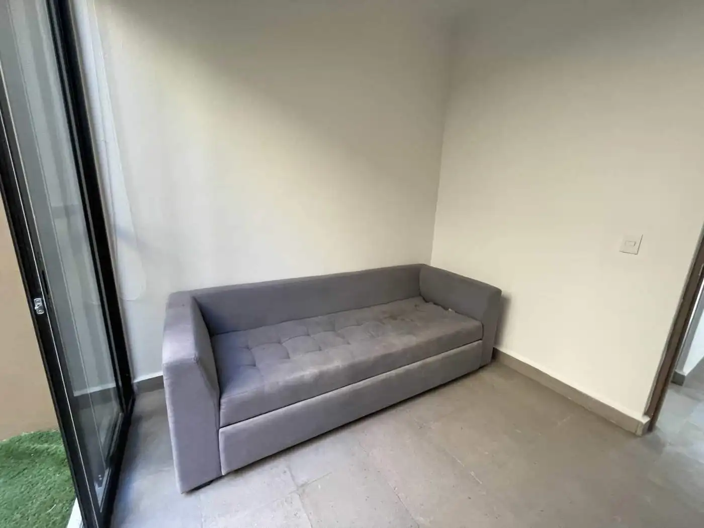 Modern gray sofa in a bright living room with large glass door.
