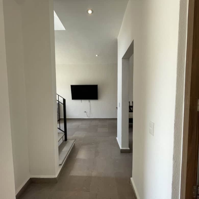 Modern interior hallway with a mounted TV in a bright, minimalist home.