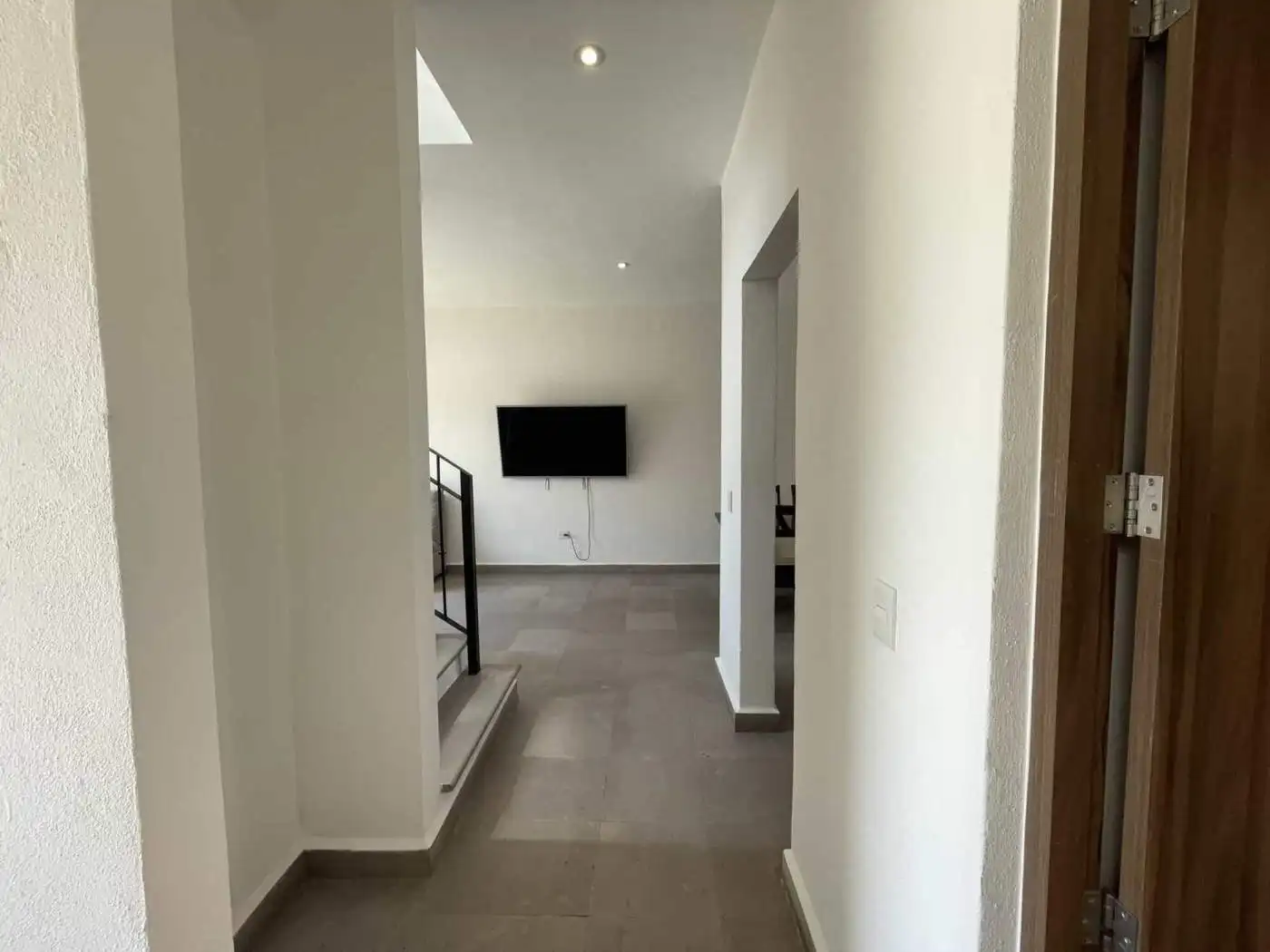 Modern interior hallway with a mounted TV in a bright, minimalist home.