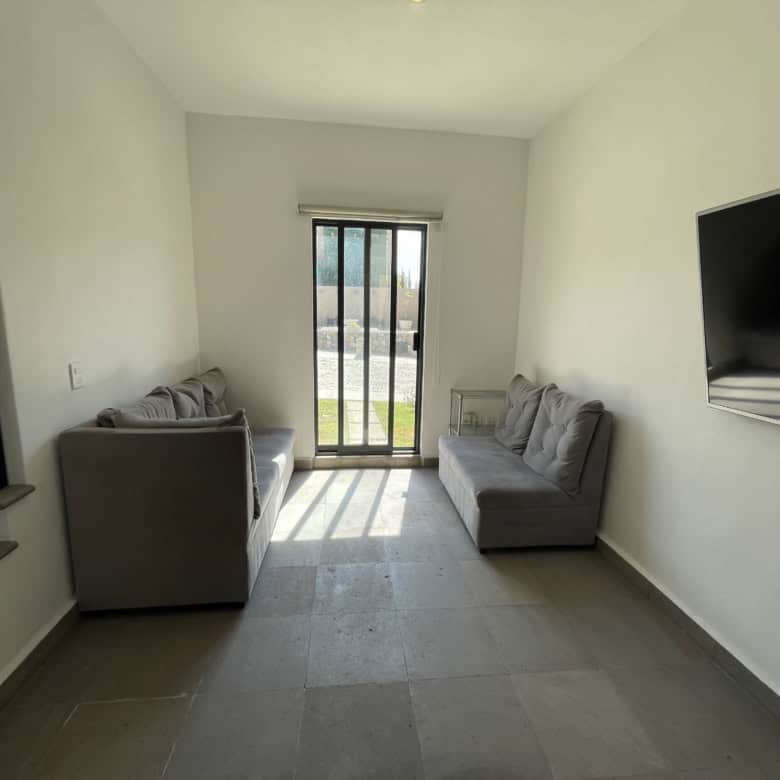 Modern living room with two gray sofas, sliding glass door, and wall-mounted TV.