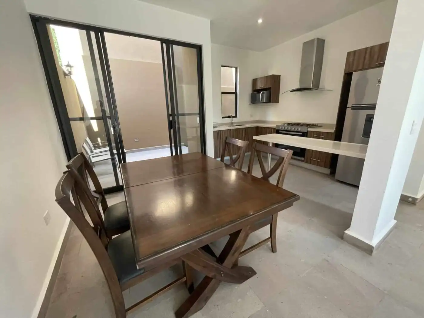 Modern kitchen and dining room with wooden table, chairs, and contemporary appliances.