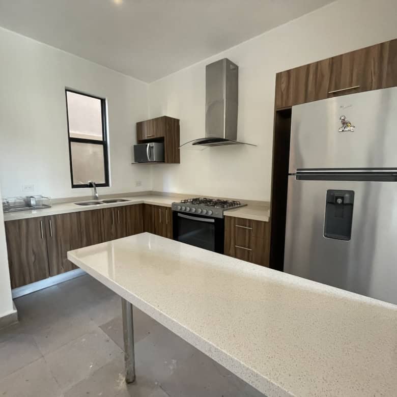 Modern kitchen with wooden cabinets, stainless steel fridge, and a central island for cooking and di.