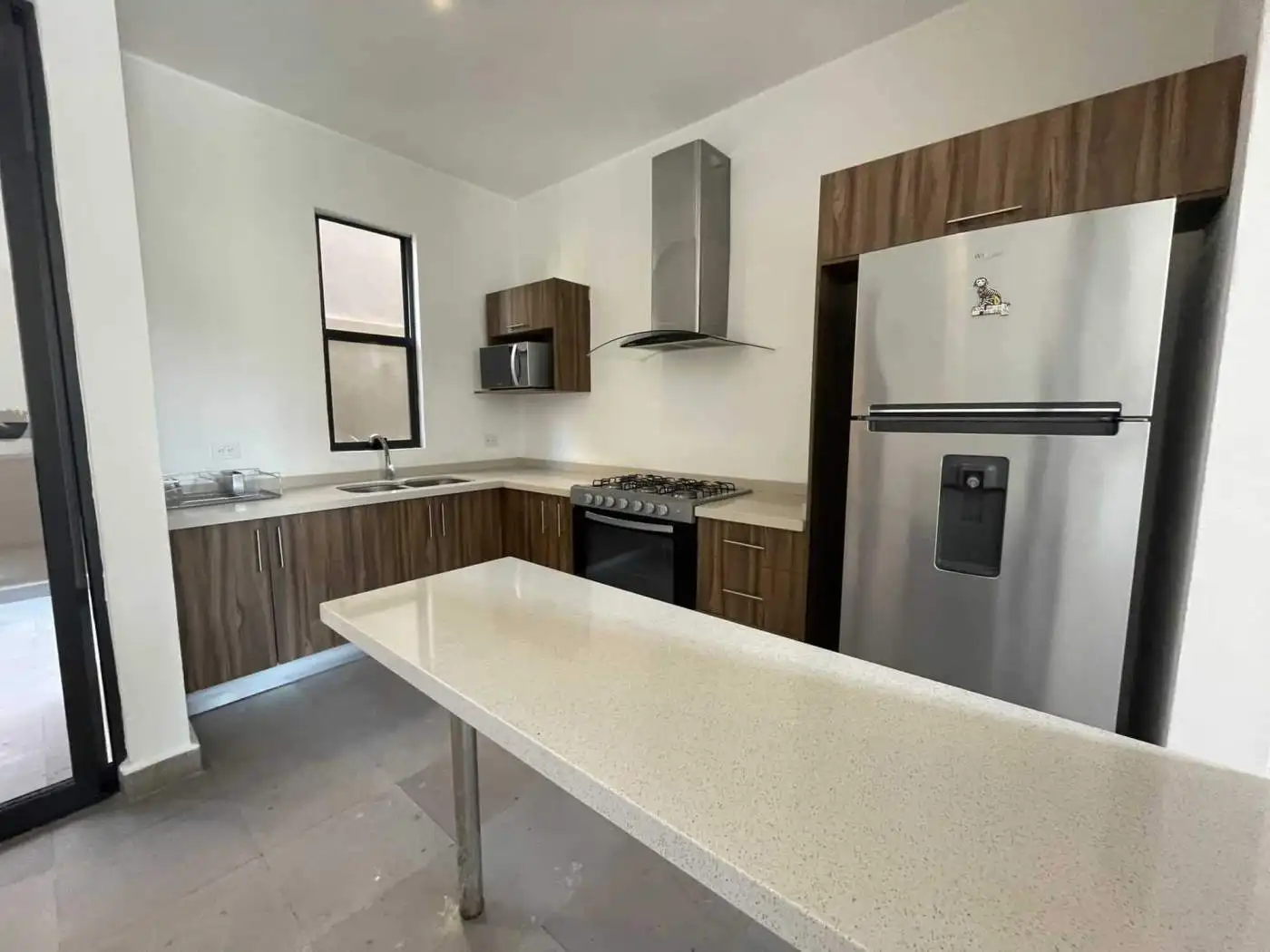 Modern kitchen with wooden cabinets, stainless steel fridge, and a central island for cooking and di.