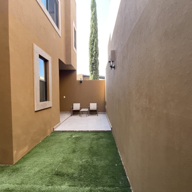 Outdoor patio with seating area and artificial grass in a modern home.