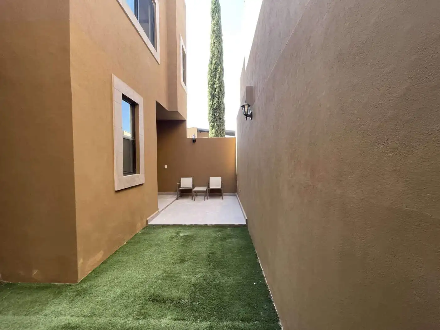 Outdoor patio with seating area and artificial grass in a modern home.