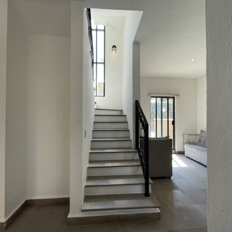Bright interior staircase with white steps and black handrail in a modern home.