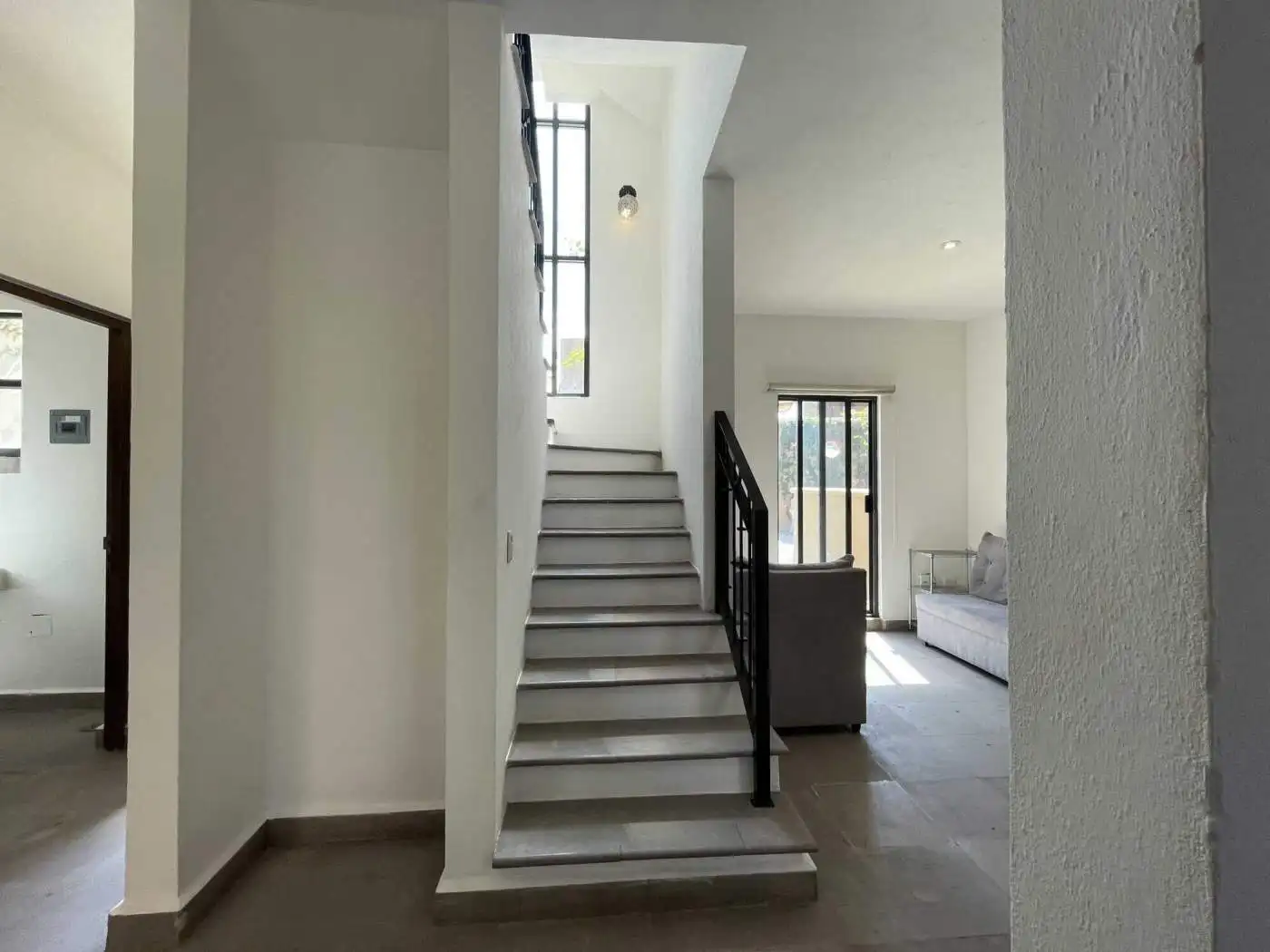Bright interior staircase with white steps and black handrail in a modern home.