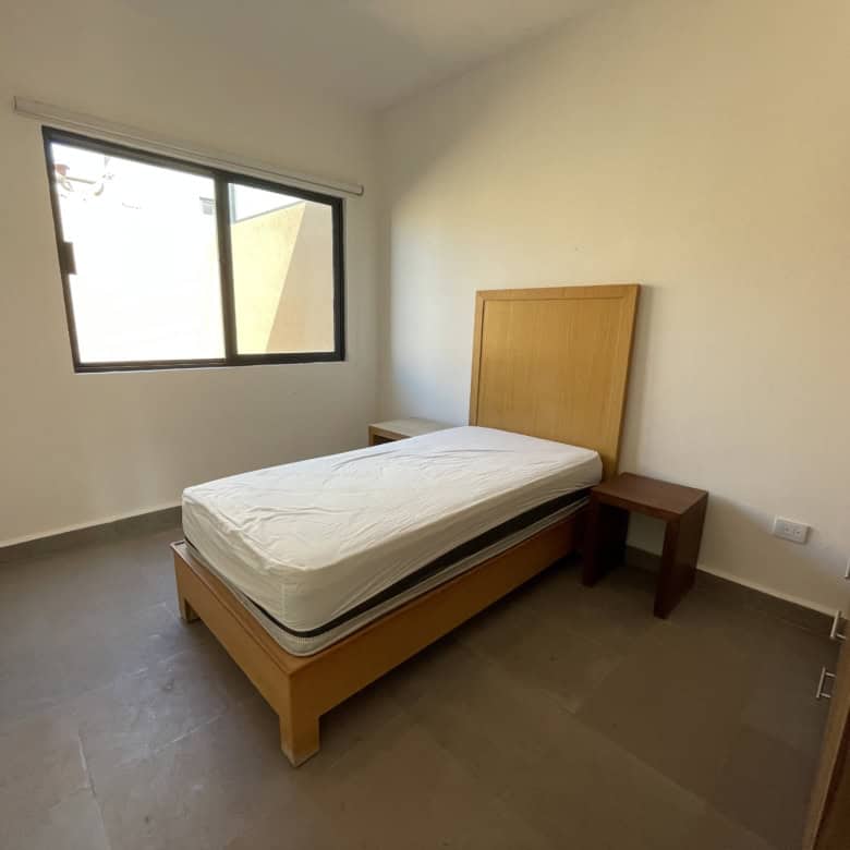 Single bedroom with bed and window in a minimalist interior.