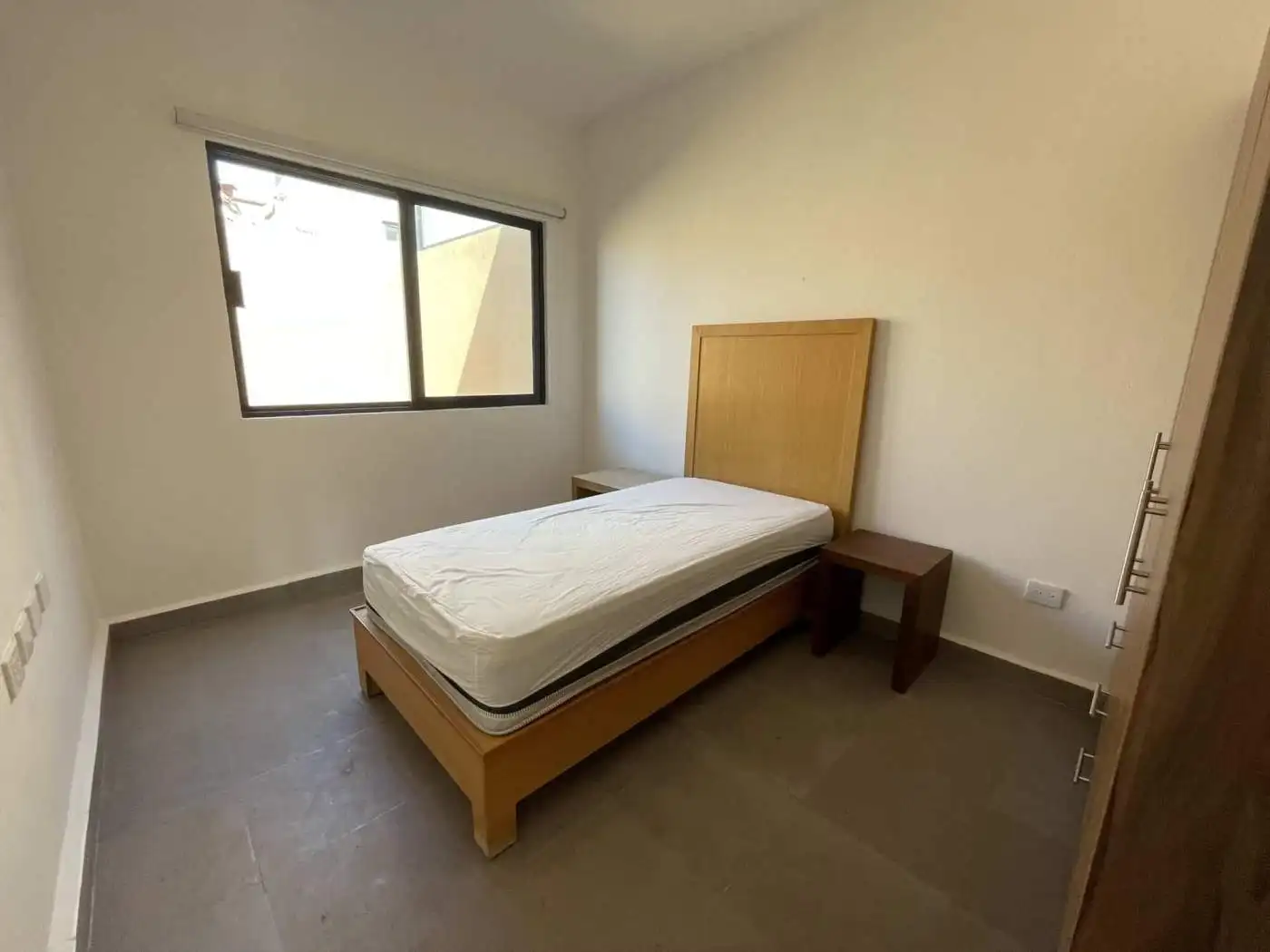 Single bedroom with bed and window in a minimalist interior.