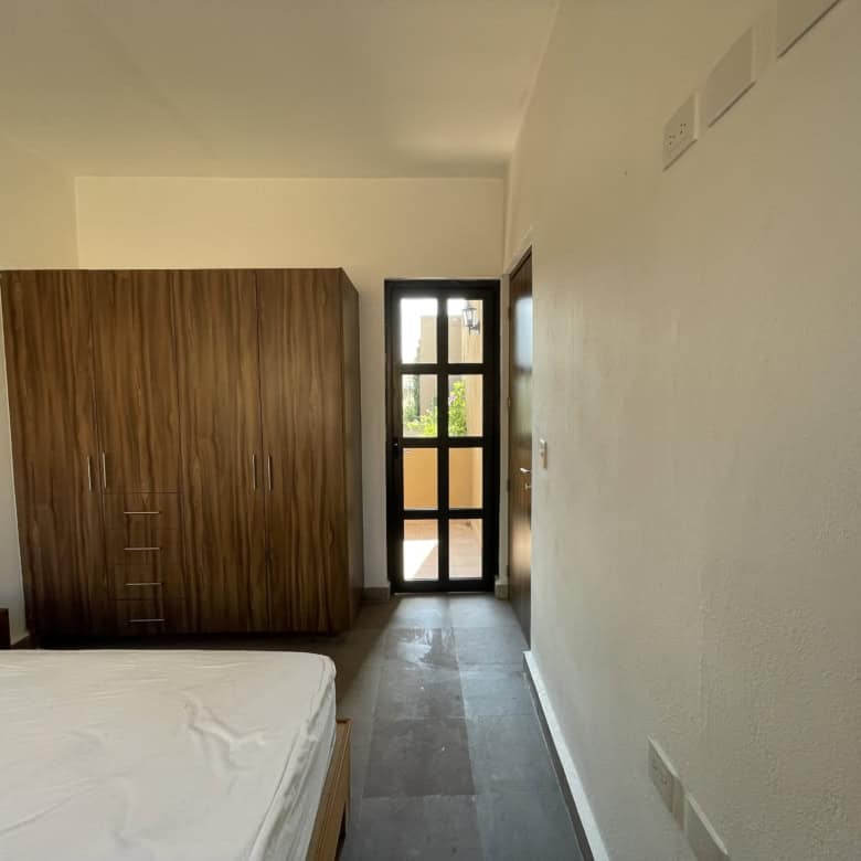Modern bedroom with wooden wardrobe and balcony door for natural light.