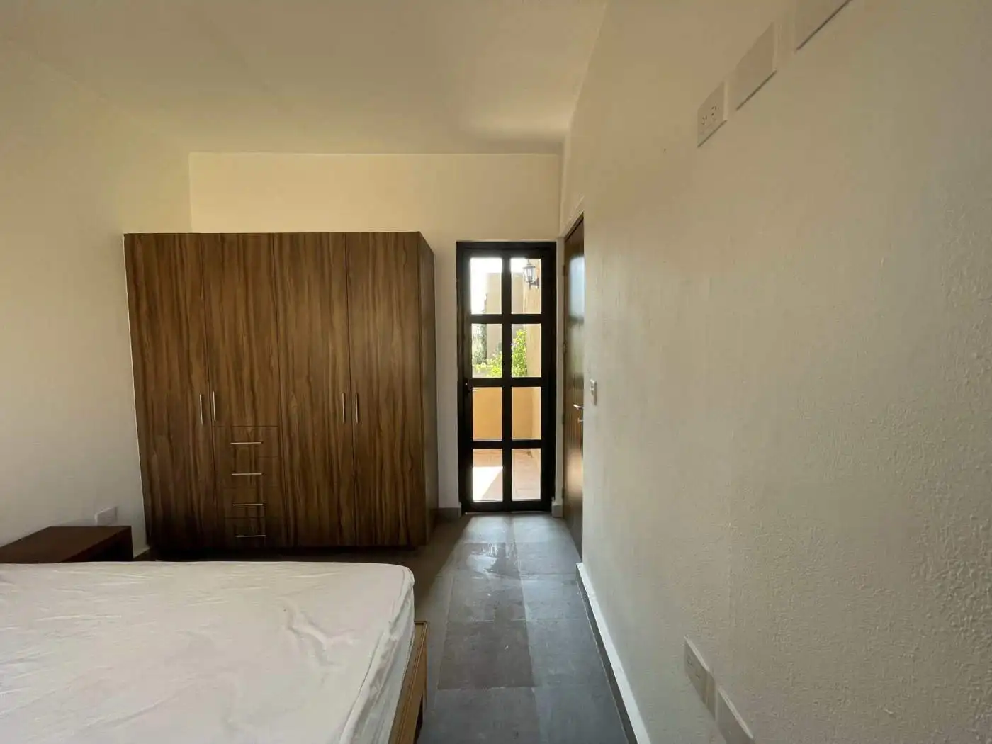 Modern bedroom with wooden wardrobe and balcony door for natural light.