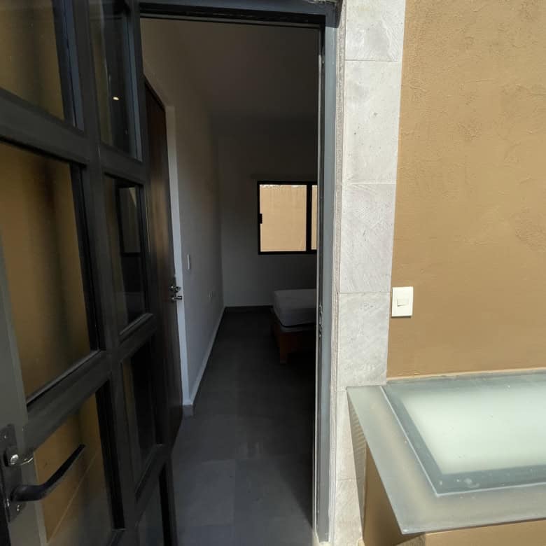 Modern apartment entrance with open door leading to a bedroom.