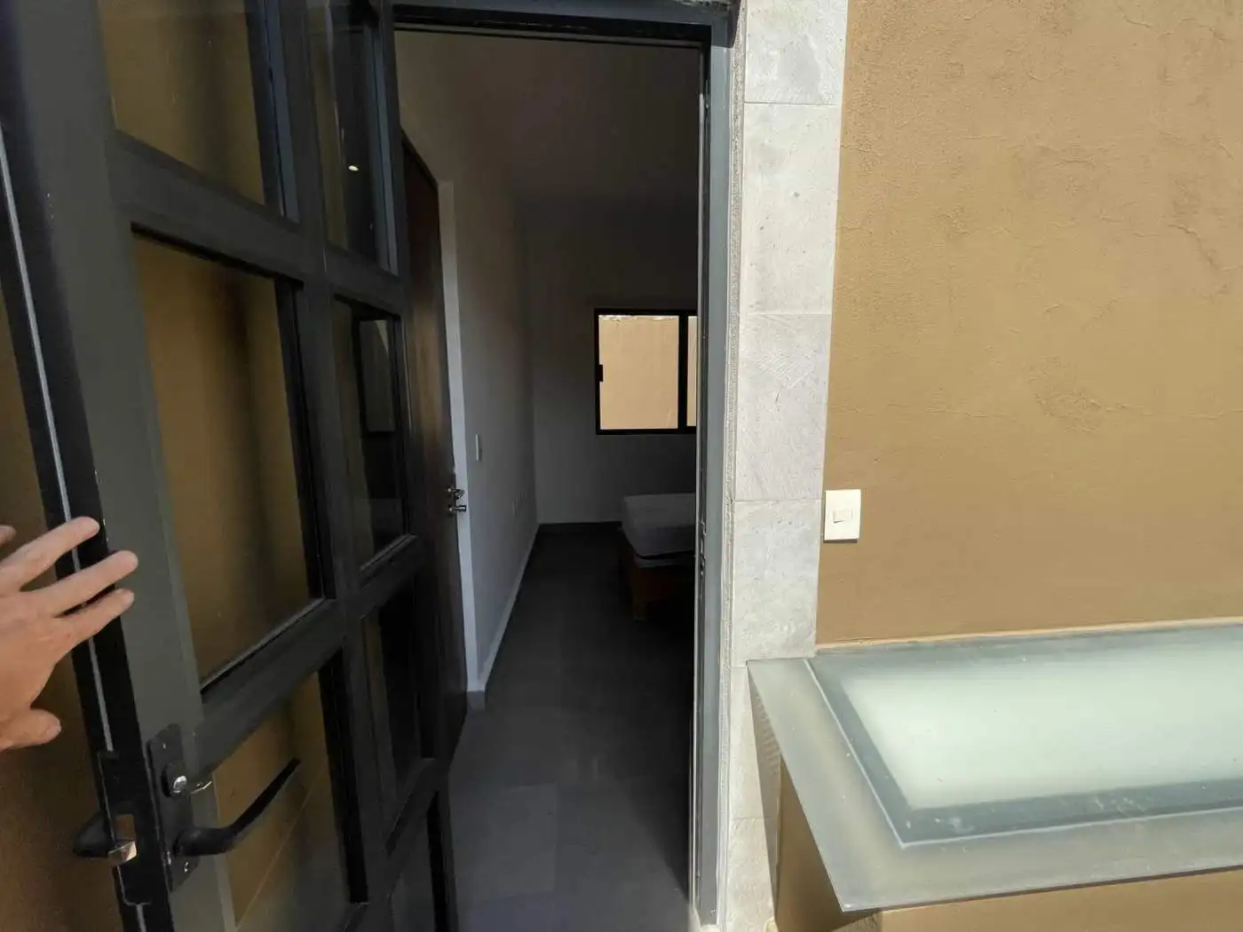 Modern apartment entrance with open door leading to a bedroom.