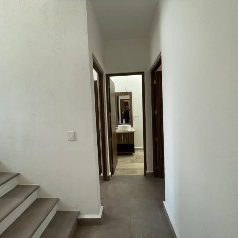 Bright hallway leading to multiple rooms and a bathroom in a contemporary home.