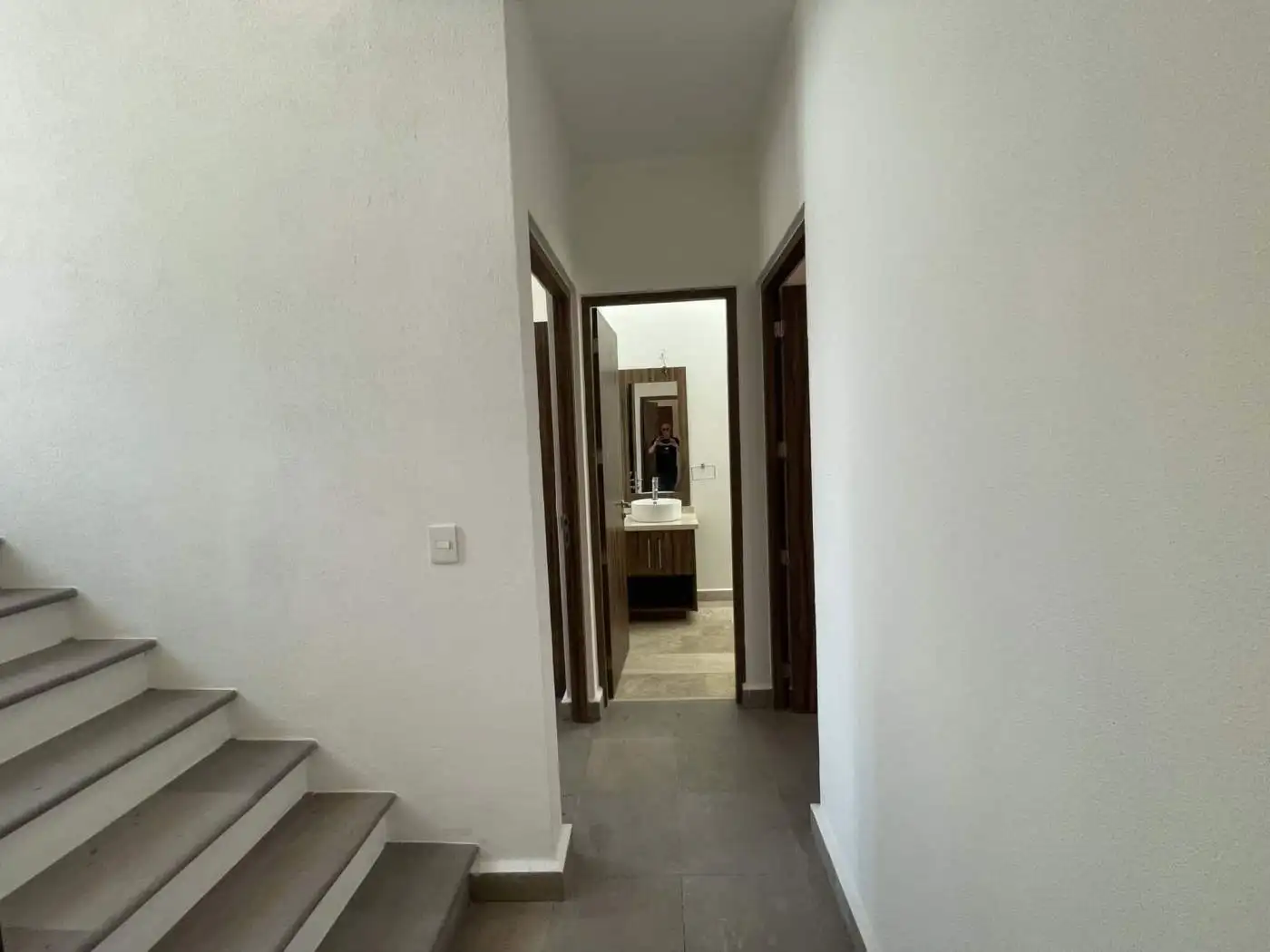 Bright hallway leading to multiple rooms and a bathroom in a contemporary home.