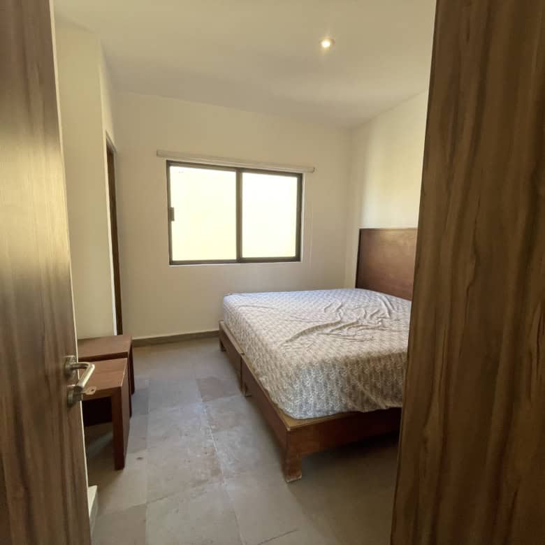 Bedroom with wooden bed frame, window, and minimal decor.