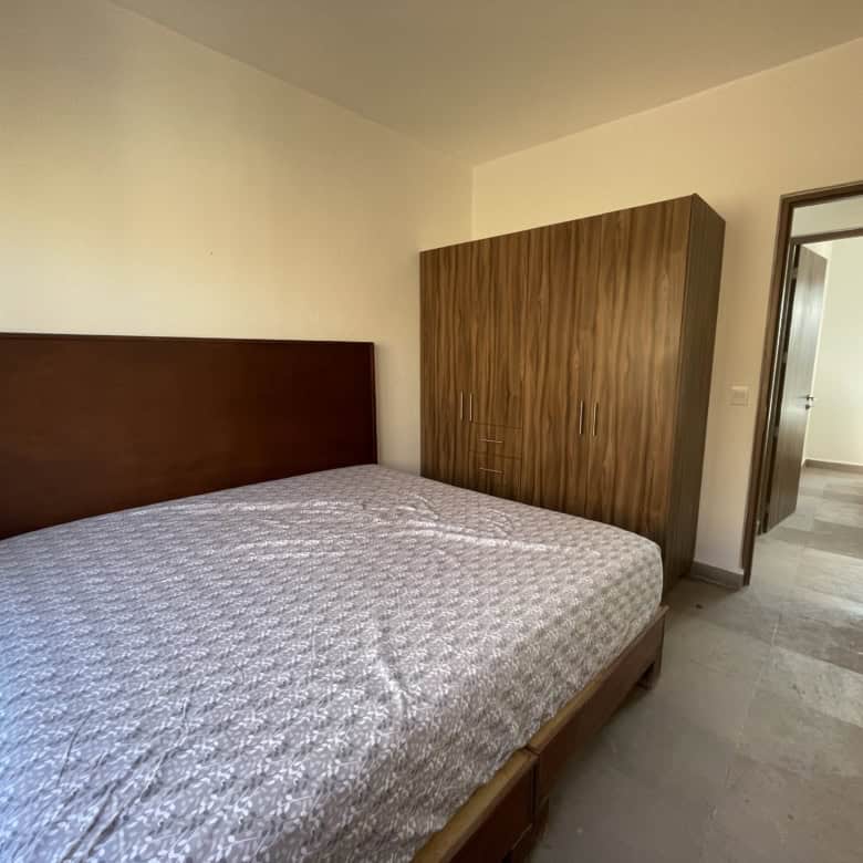 Spacious bedroom featuring a wooden bed frame and wardrobe, with an open door leading to another roo.