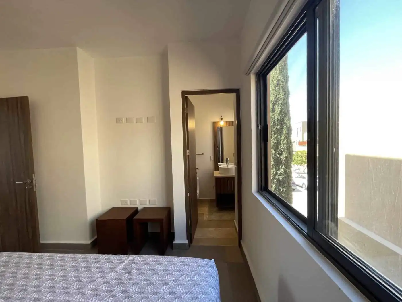 Modern bedroom with large window and en-suite bathroom for sale.