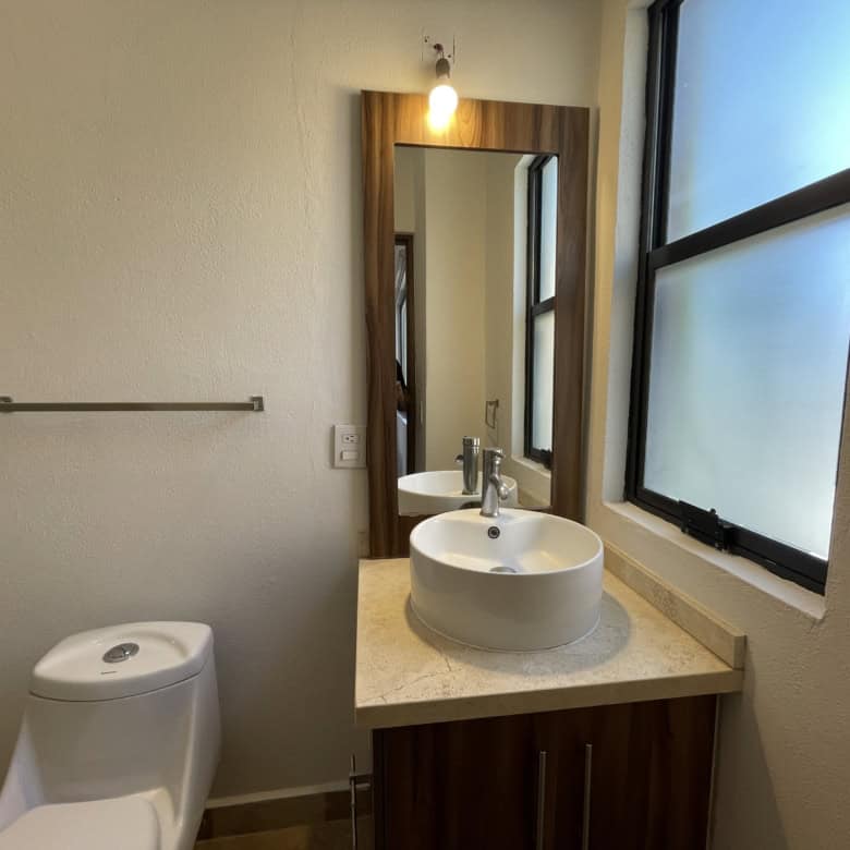 Modern bathroom with round vessel sink and large frosted window for privacy.