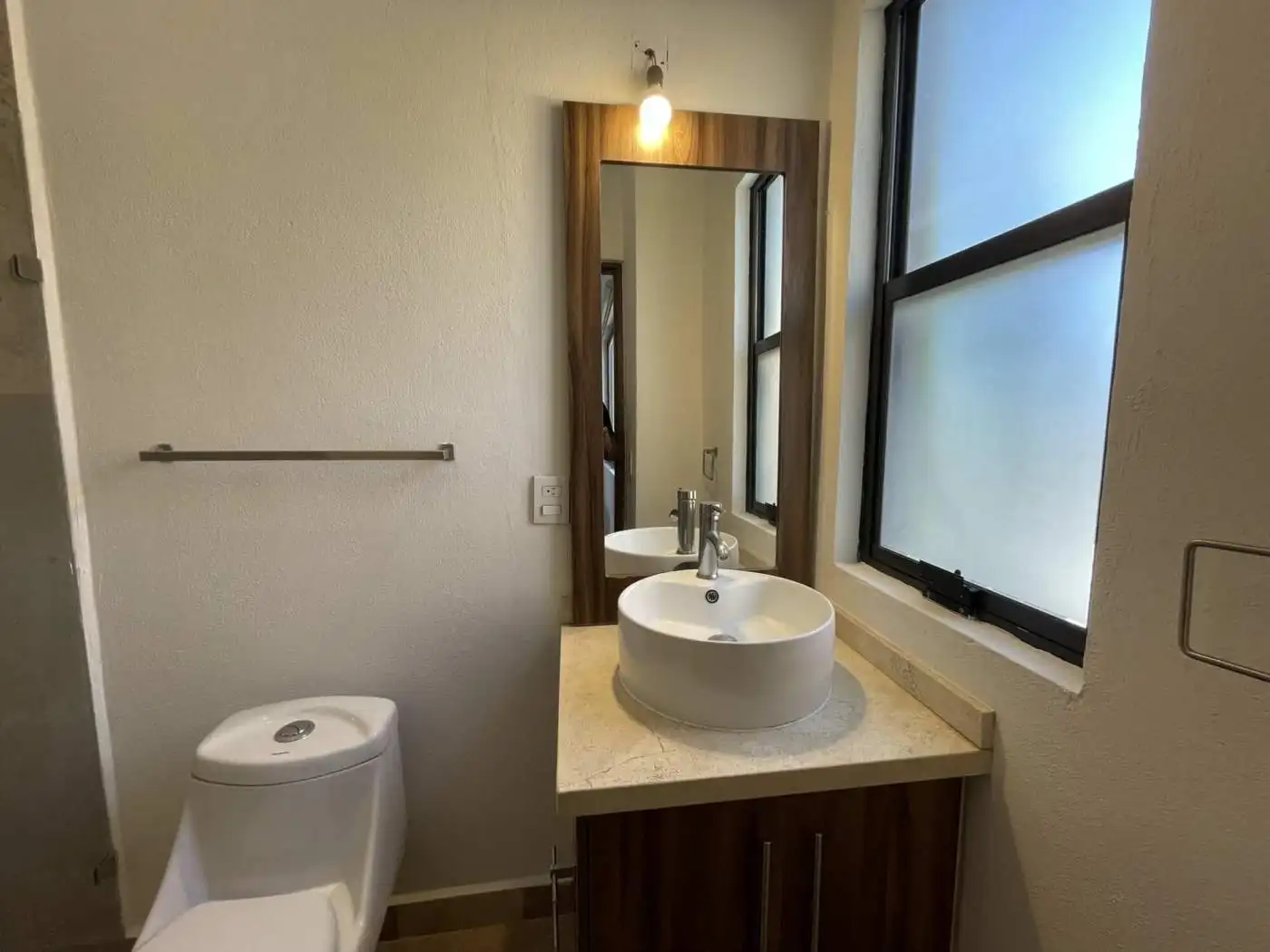 Modern bathroom with round vessel sink and large frosted window for privacy.