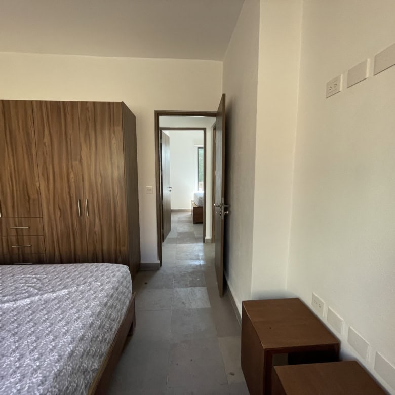 Bedroom with wooden wardrobe and simple furnishings, bright and airy interior design.