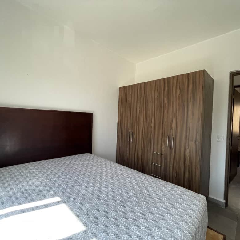 Spacious bedroom featuring a wooden wardrobe and sunlight streaming through the window.