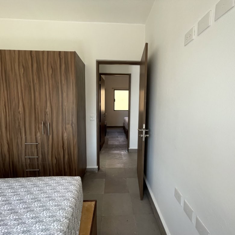 Bedroom with wooden wardrobe and open door leading to a bright interior space.
