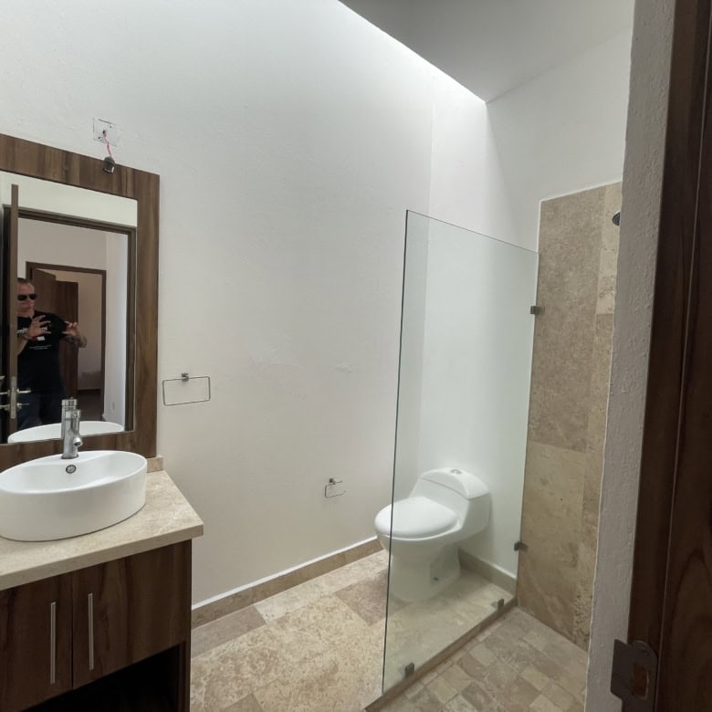 Modern bathroom with white sink, mirror, and toilet in a contemporary home.