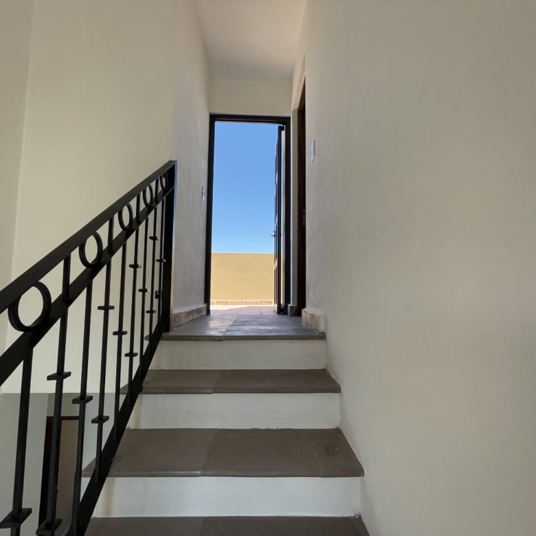 Interior staircase leading to an outdoor balcony or terrace with a view of the sky.