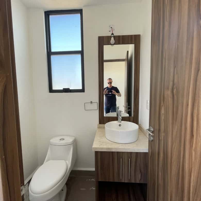 Modern bathroom with wooden accents, a white toilet, and a stylish sink with a mirror.