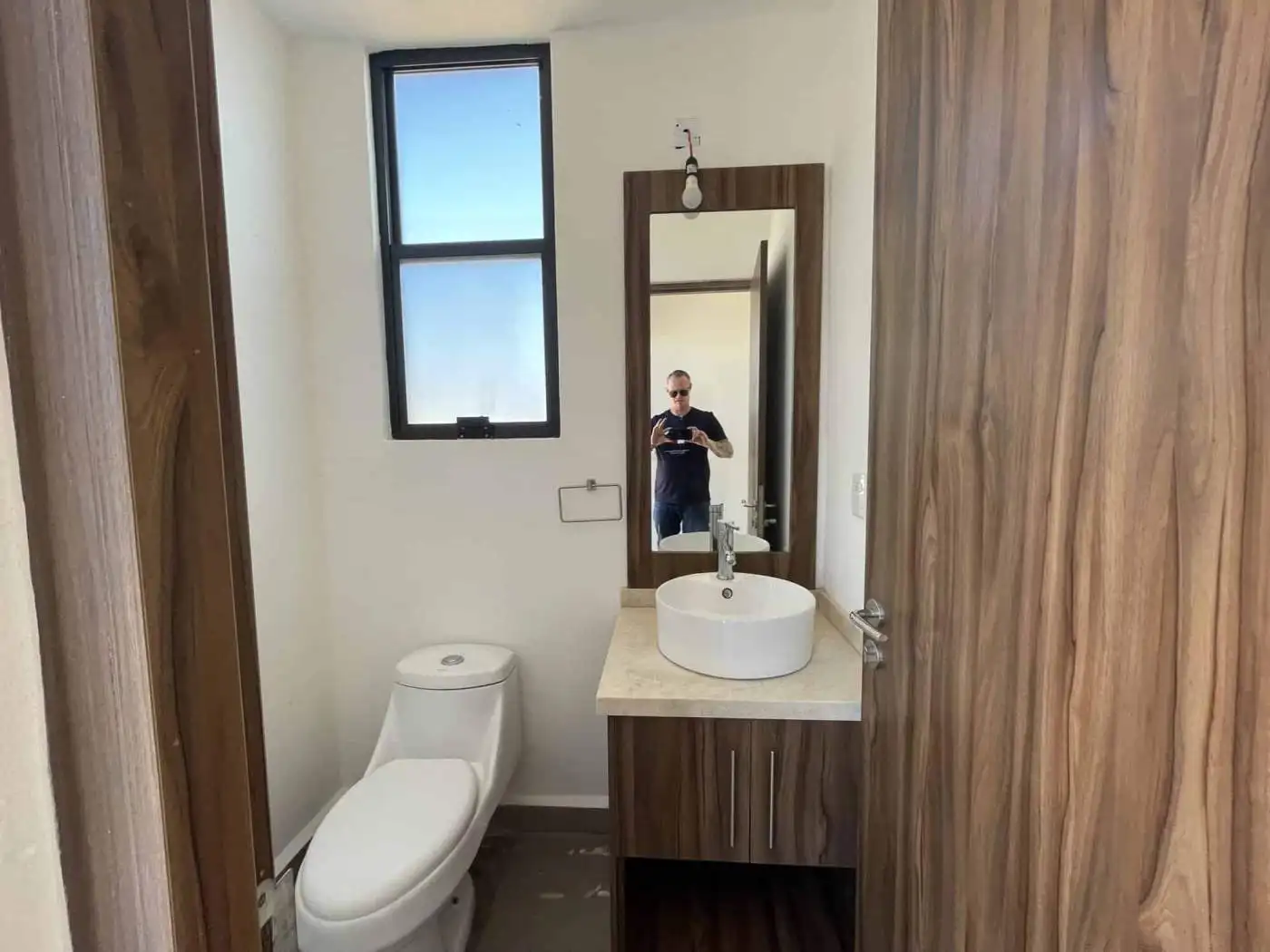 Modern bathroom with wooden accents, a white toilet, and a stylish sink with a mirror.