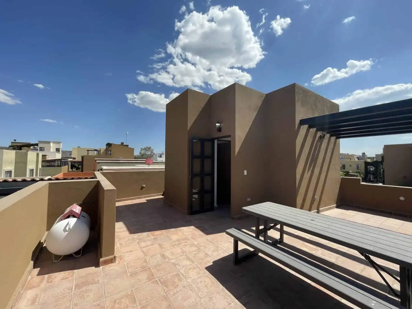 Rooftop terrace featuring outdoor seating, city skyline views, and a clear blue sky. Perfect for rel.