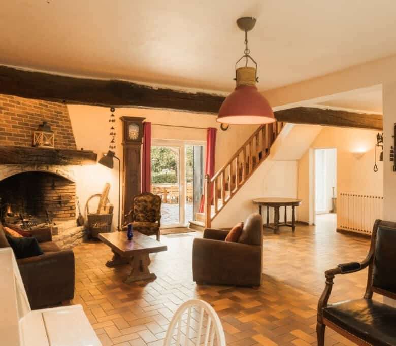 Spacious living room with rustic brick fireplace, wooden beams, and cozy seating in a beautiful esta.