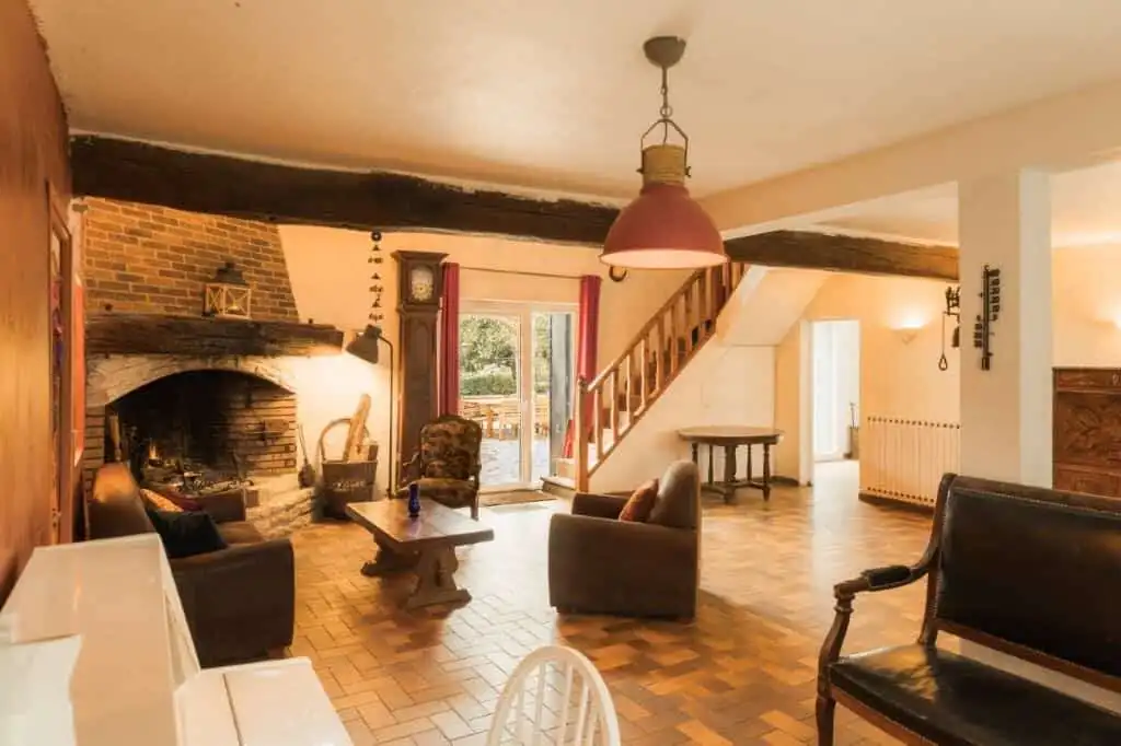 Spacious living room with rustic brick fireplace, wooden beams, and cozy seating in a beautiful esta.